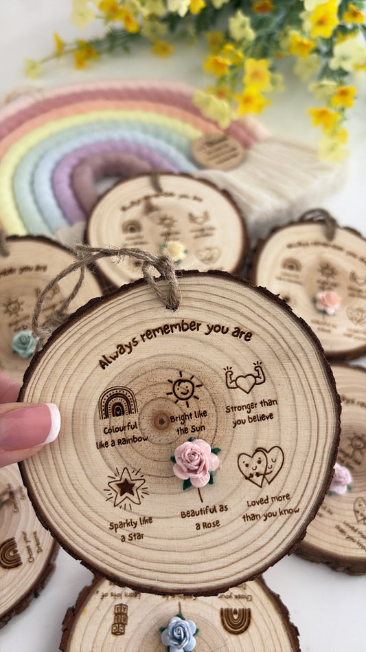Natural wooden affirmation keepsake disc featuring the words "Always Remember You Are" with rainbow, sun, star, heart and rose illustrations, finished with a handcrafted flower and rustic twine.
