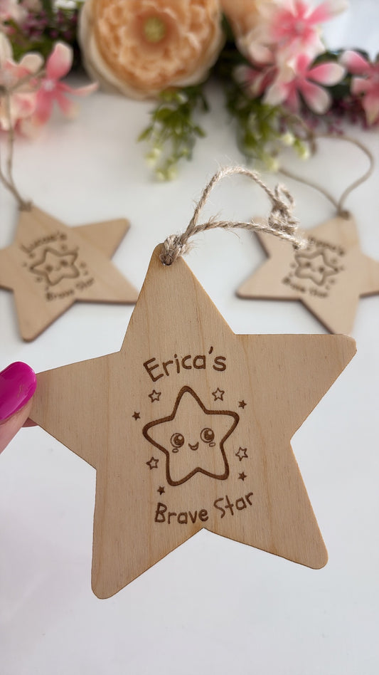 Personalised wooden star keepsake engraved with a child's name and "Brave Star", featuring a cute smiling star illustration and rustic twine hanging loop.