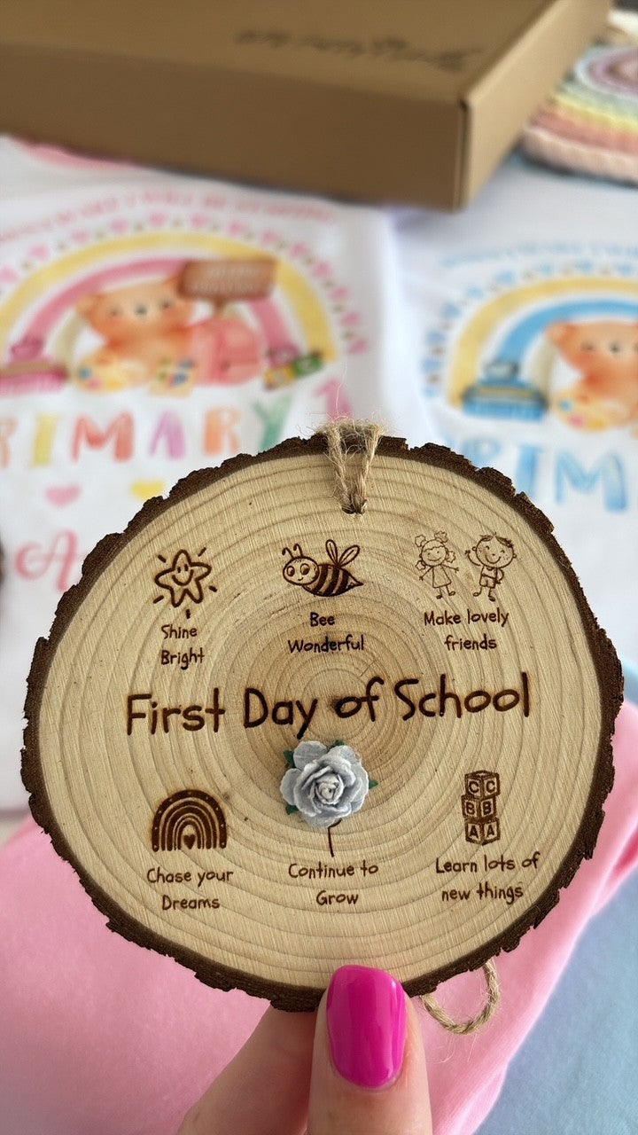 Personalised First Day of School Wooden Disc engraved with a child's name and class, featuring exclusive Aaliyah's Rainbow illustrations and a blue flower, handcrafted on a natural wood slice with twine for hanging. Perfect for back-to-school photos and keepsake memories.