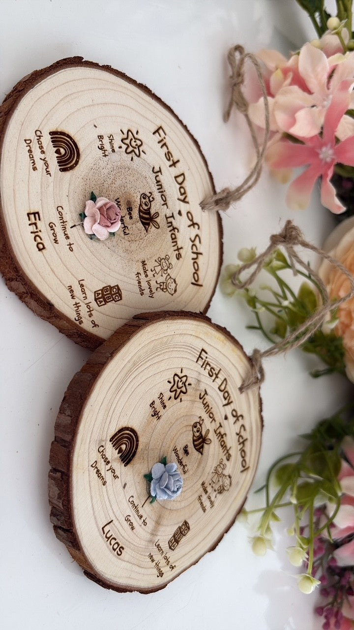 Two personalized wooden log slice wall hangings with engraved names, dates, and small flower accents, displayed on a white surface with decorative flowers in the background.