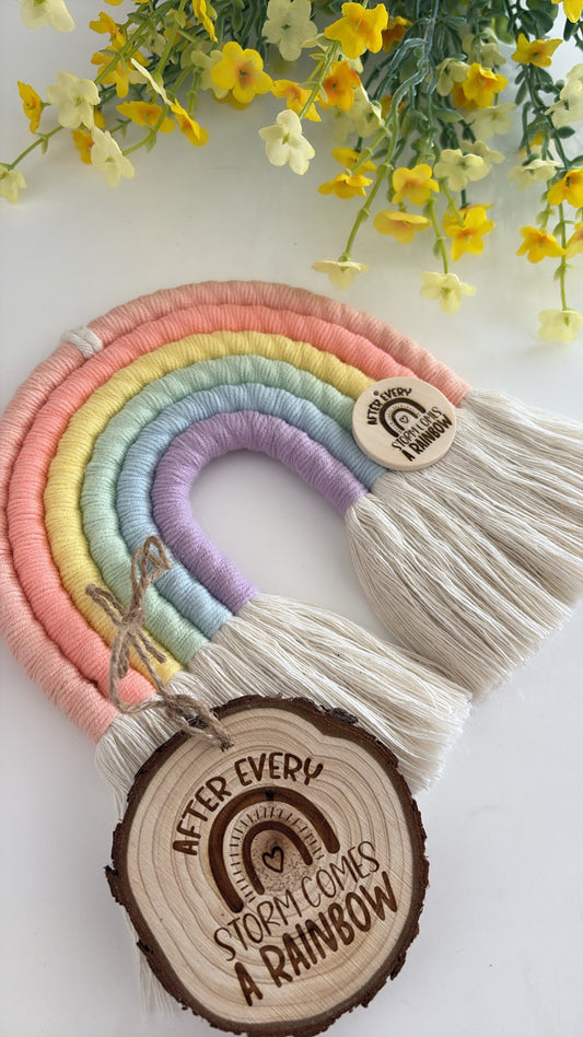 Handmade pastel macrame rainbow wall hanging with engraved wooden tag that reads ‘After every storm comes a rainbow