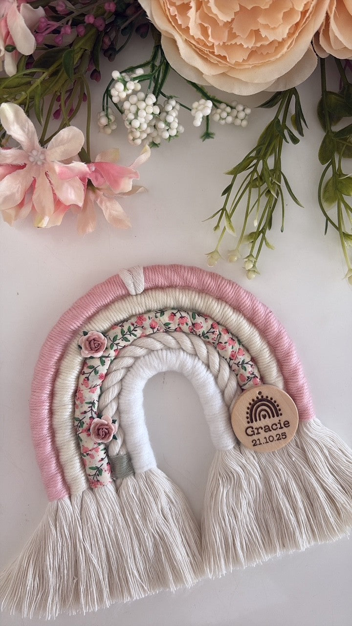 Personalised macramé rainbow baby gift in soft pink, cream and ditsy floral print with wooden engraved tag.