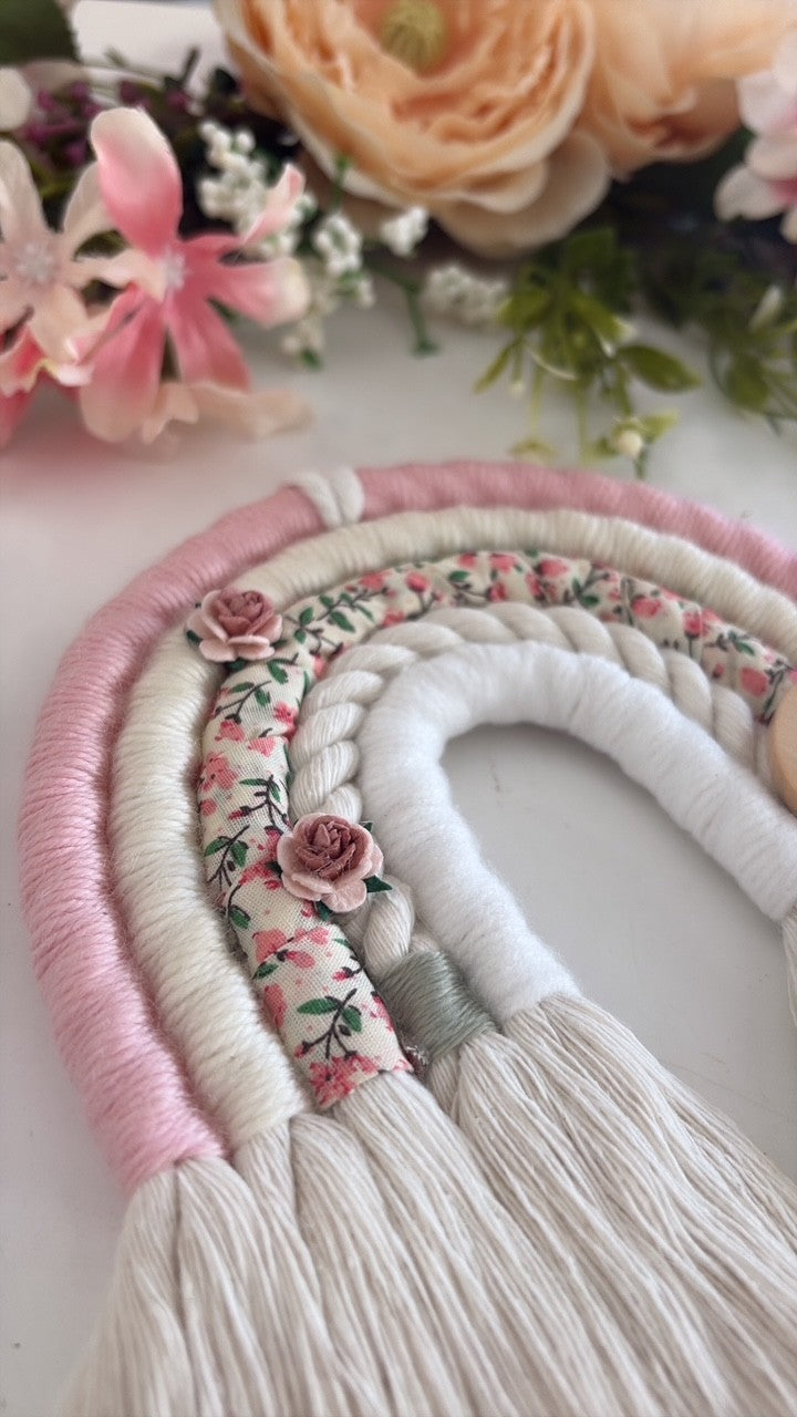 Personalised macramé rainbow baby gift in soft pink, cream and ditsy floral print with wooden engraved tag.