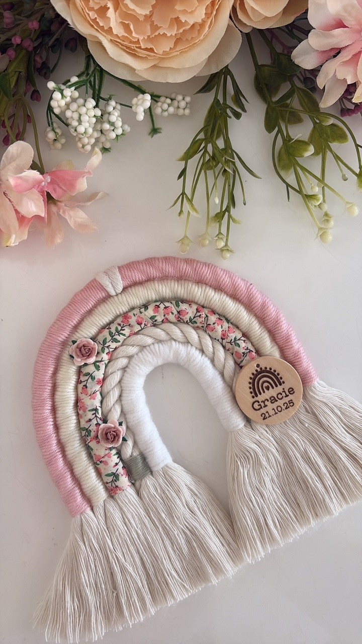 Personalised macramé rainbow baby gift in soft pink, cream and ditsy floral print with wooden engraved tag.