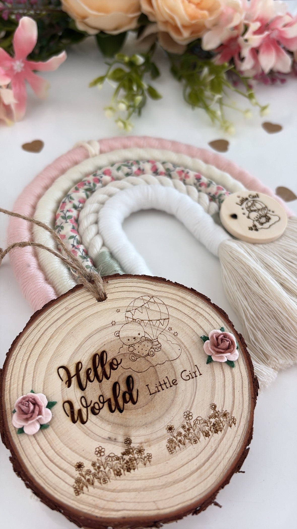 Handmade pink and floral macrame rainbow wall hanging with wooden tag engraved ‘Hello World, Little Girl,’ beautifully wrapped and ready for gifting