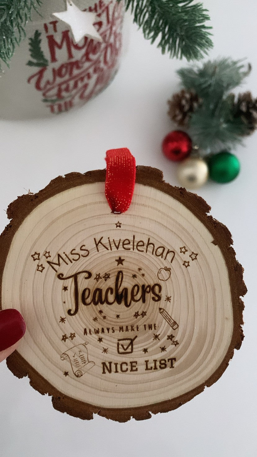 Wooden engraved disc with “Teachers Always Make the Good List” text and festive doodle design on natural wood.